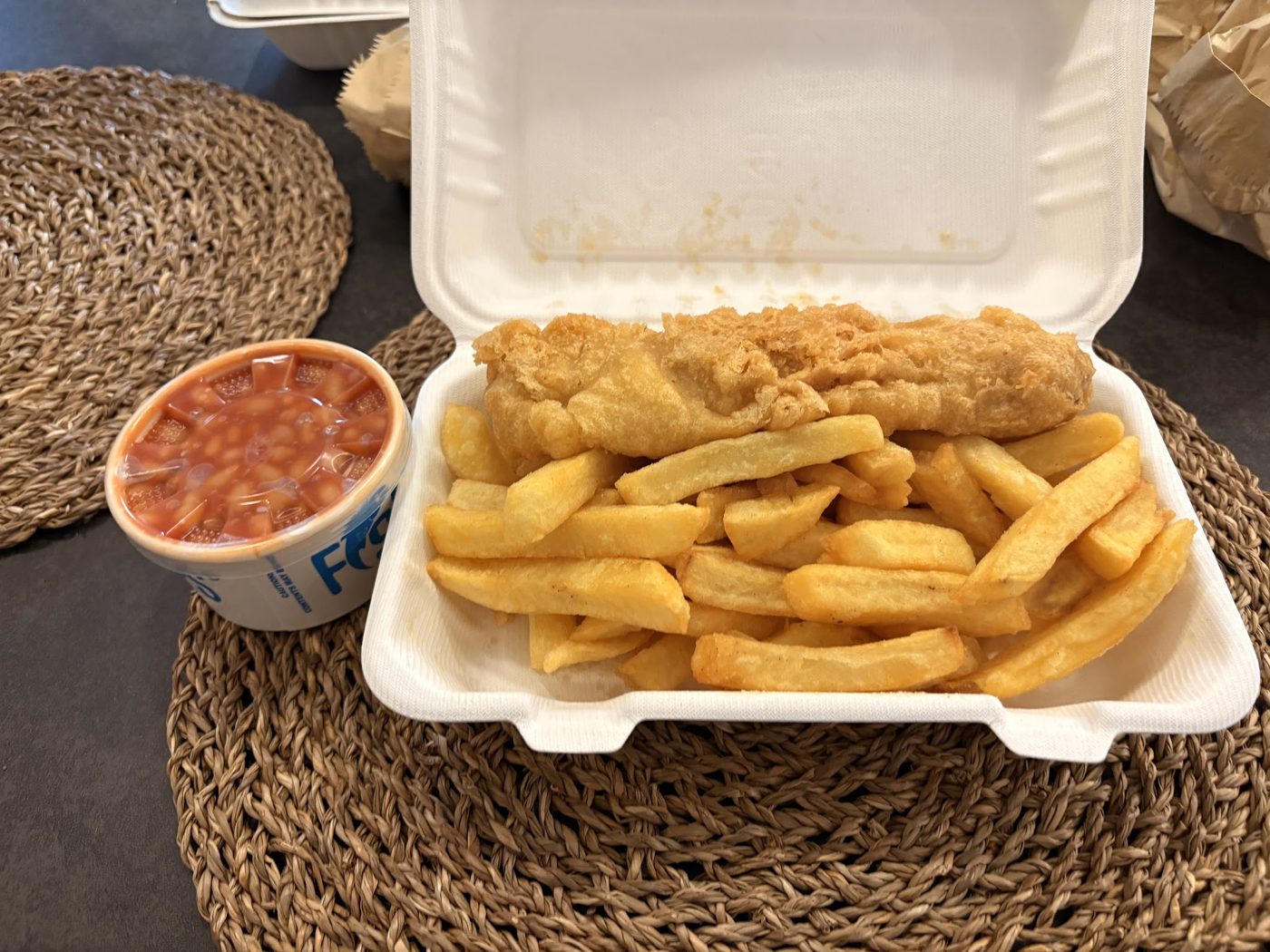 Fish and chips in a box with a pot of beans