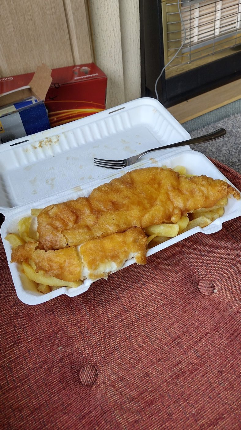 Fish and chips in a takeaway box with a fork