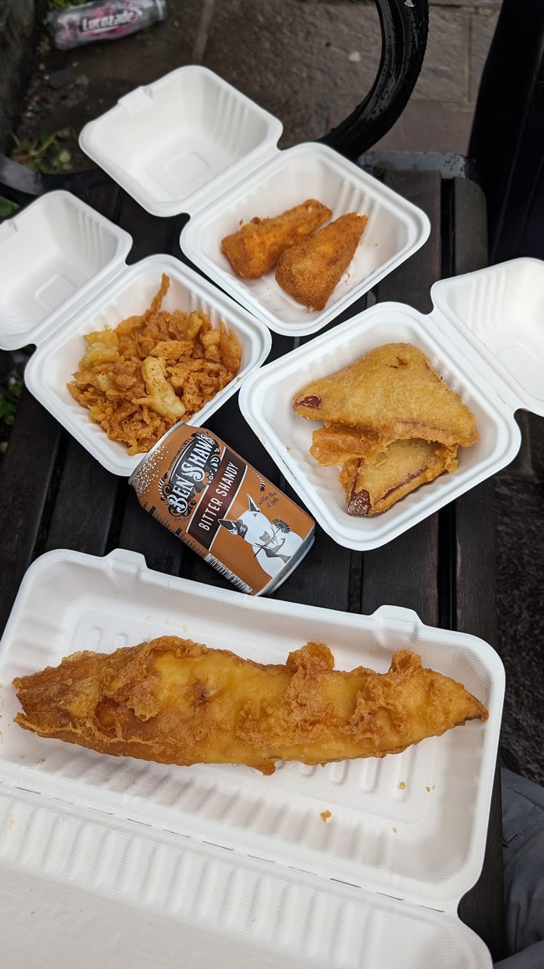 Several takeaway boxes with fish, chicken and a spring roll